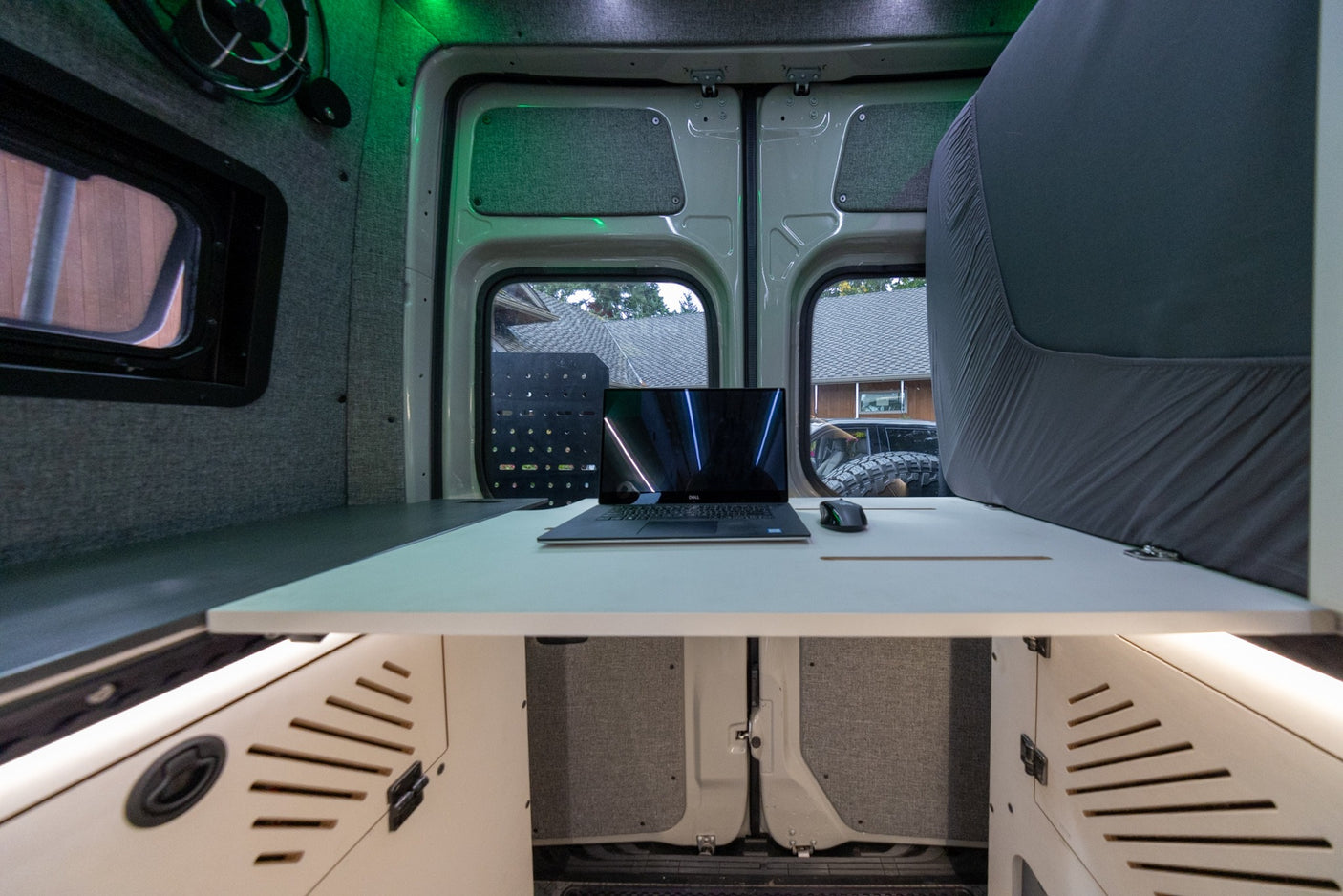 RV rental: Workstation with laptop, mouse, and green ambient lighting inside a modern camper van interior.