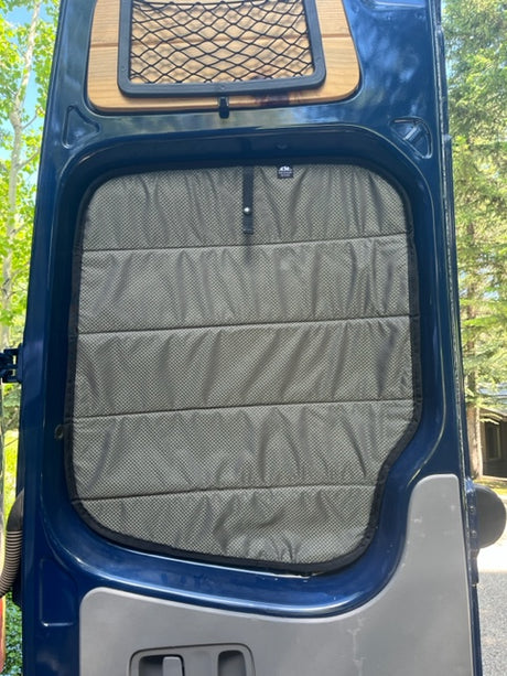 RV rental interior: Customized van door featuring a quilted window cover and a handy mesh storage net.