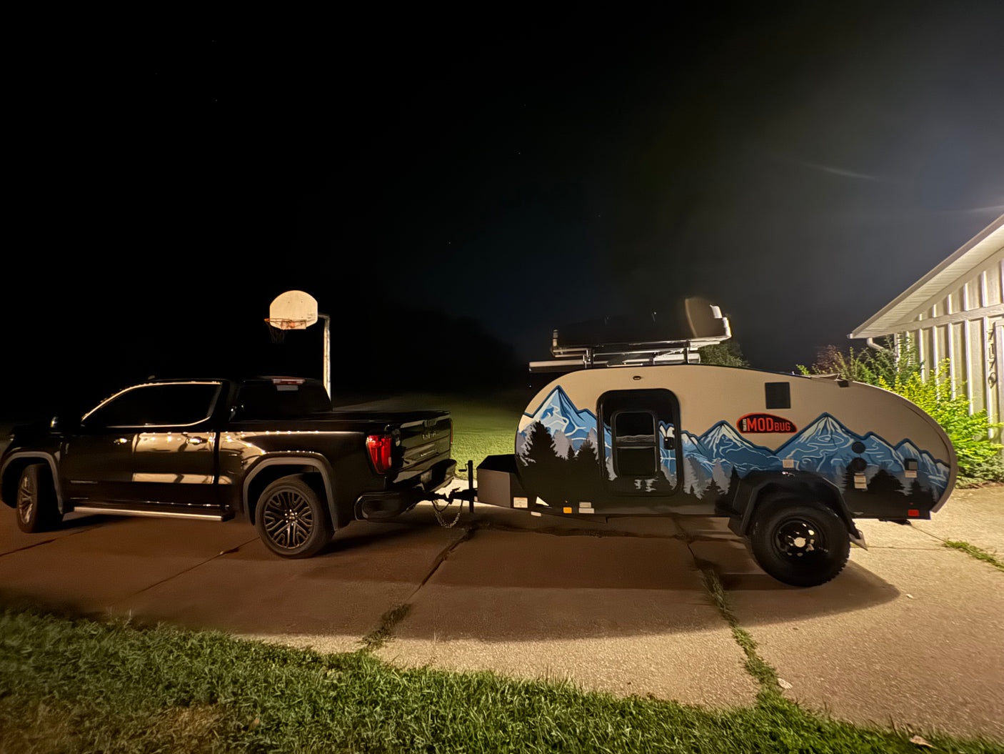 Towing an RV rental: A black pickup truck hitched to a Modbug teardrop travel trailer at night, ready for adventure.
