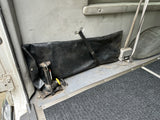 RV rental utility zone: jack, secured black storage bag, and seatbelt in a vehicle interior with a textured floor mat.