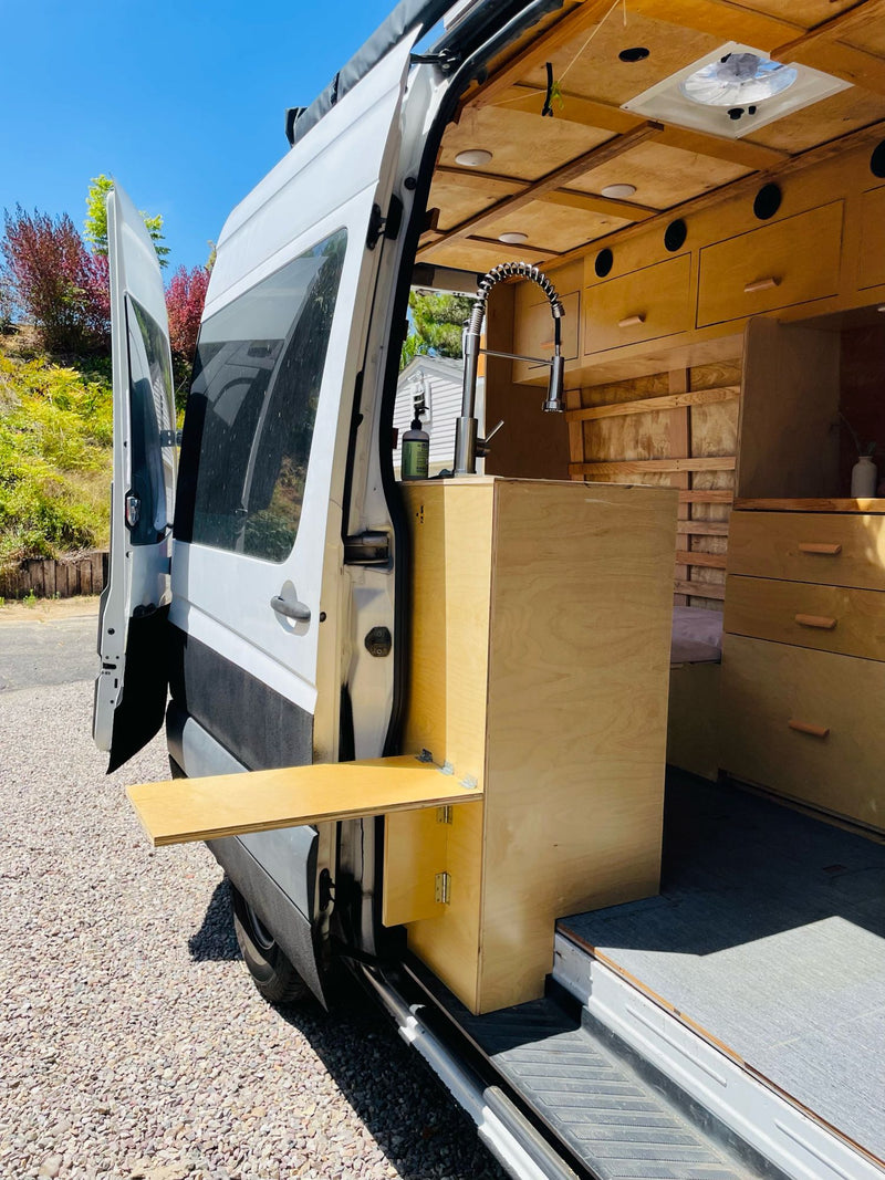 RV rental: Custom Sprinter van conversion featuring a clever exterior table, sink, and warm wood interior. — photo 8
