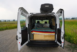 This camper van interior, ideal for an rv rental, features a bed, storage, and Thule roof box, ready for nature adventures.