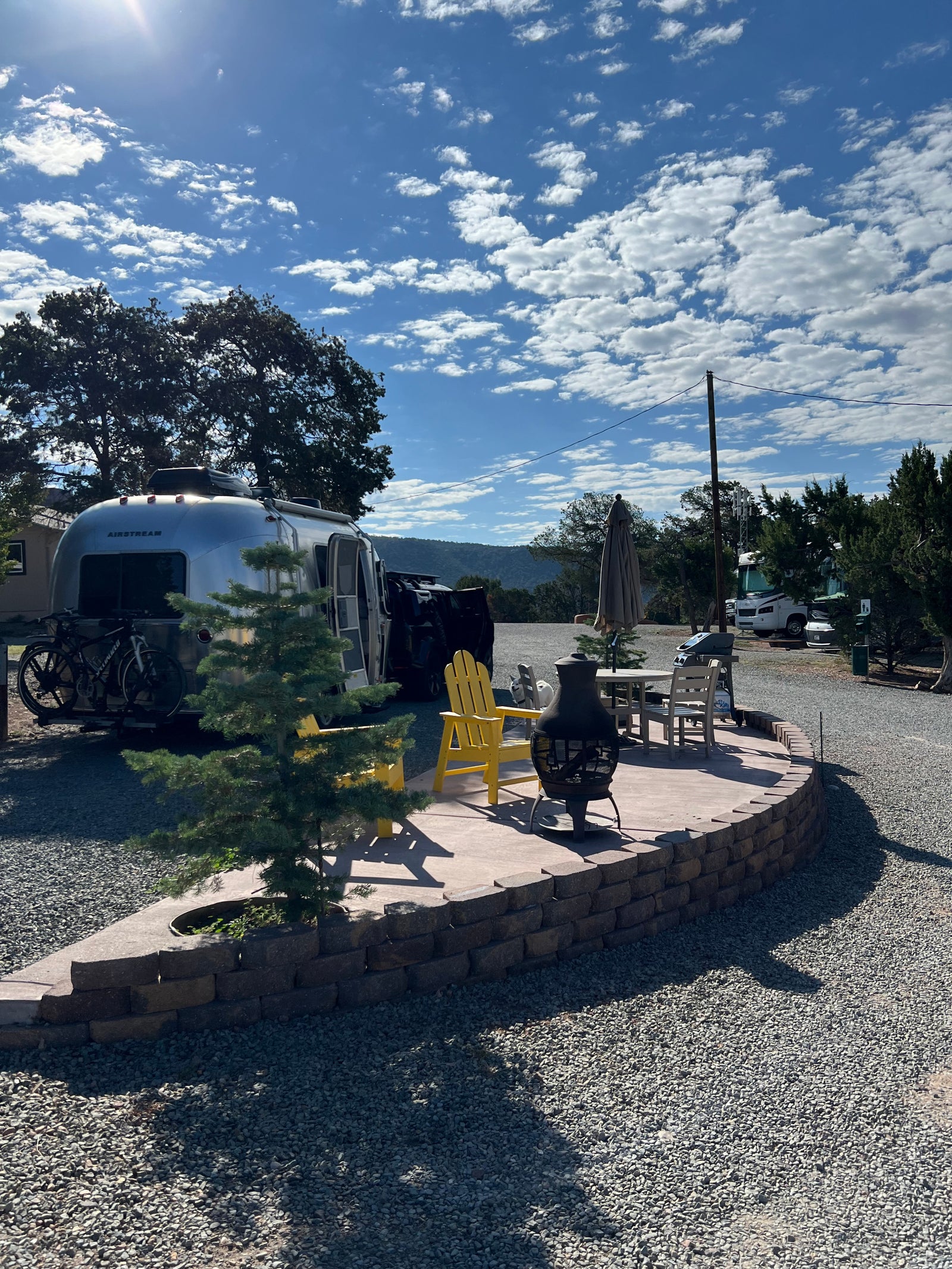 Your RV rental adventure begins here! A gleaming Airstream and bikes with a comfortable patio, chairs, and fire pit.