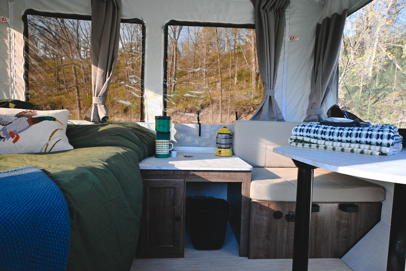 Inviting RV rental interior: bed, dining area, and forest views. A cozy escape for your next road trip adventure. — photo 3