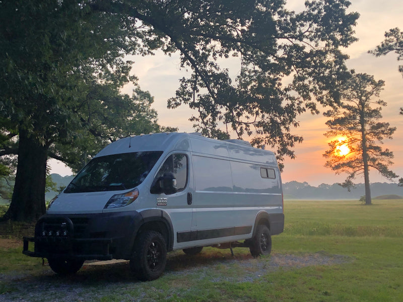 RV rental van at sunrise in a peaceful, misty field with large trees, ready for adventure. — photo 11