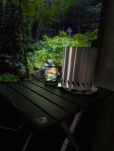 Inside your **rv rental**: a cozy retreat with a projected forest view, portable stove, and warm-lit glass on a table.