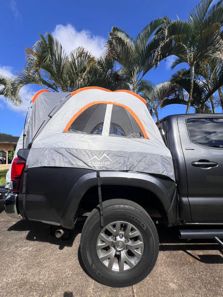 Dark grey truck with KARMATER truck bed tent under palm trees, an alternative to an RV rental for outdoor camping.