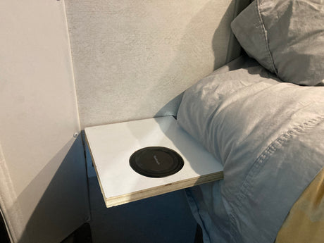 RV rental bedroom detail: a built-in shelf with a Yootech charger next to cozy gray bedding.