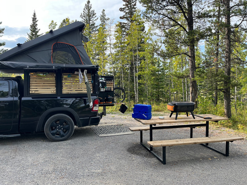 An overlanding truck w/ rooftop tent and camp kitchen at a forest campsite. Ideal for your next RV rental escape! — photo 11