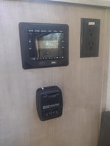 RV rental interior: Jensen media panel, Suburban thermostat, and power outlet on the wall, managing onboard systems.