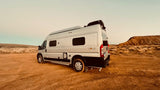 Explore the open road with an RV rental! A silver camper van in a rugged desert, perfect for your next adventure.