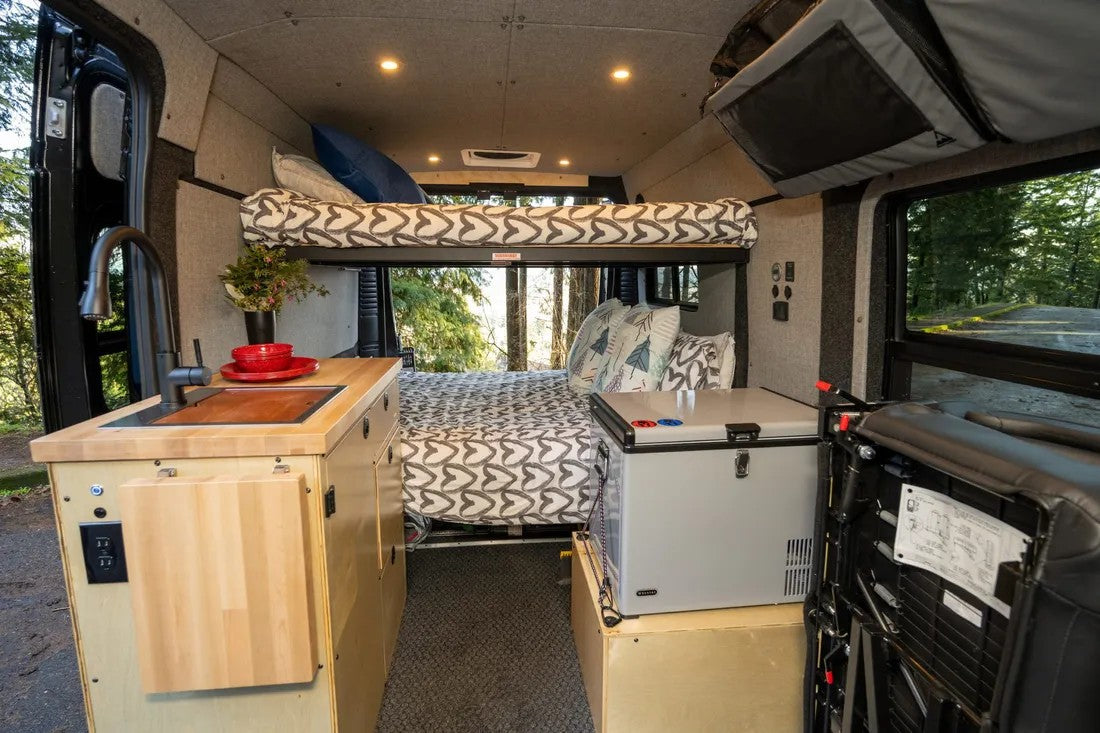 RV rental interior: compact kitchenette, upper & lower beds, and fridge, perfect for comfortable camper van trips.