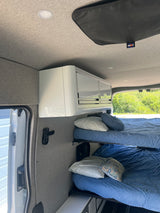 Inside this comfy RV rental, featuring bunk beds, sleek white overhead storage, and a scenic window view.