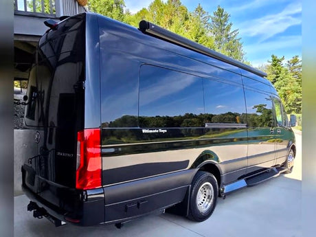 Sleek black Mercedes-Benz Sprinter luxury rv rental. A custom, spacious van with tinted windows and an awning.