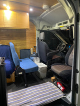 An RV rental interior featuring warm wood, comfortable seating, overhead storage, and safety essentials like a fire extinguisher.