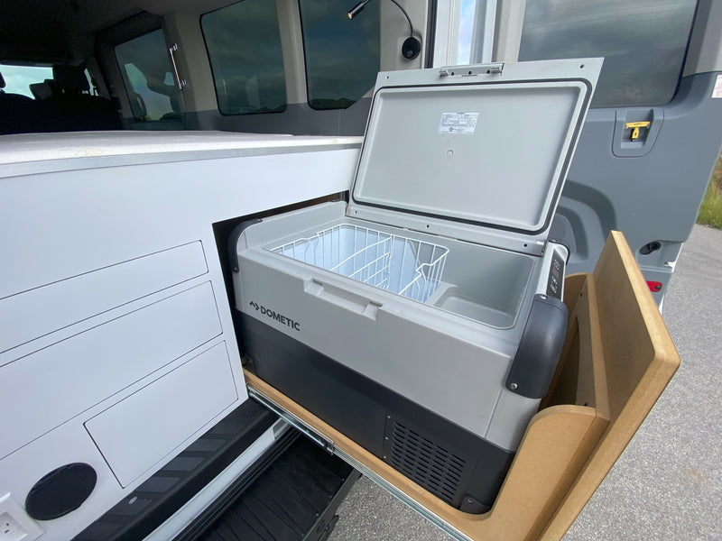 An open Dometic portable fridge/freezer on a slide-out tray inside an RV rental's custom storage area, with vehicle door open. — photo 14