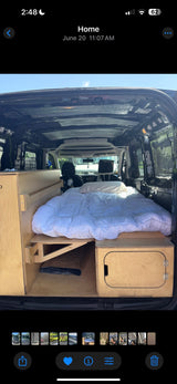 Inside a customized RV rental van: a comfy bed and built-in wooden storage, perfect for road trips.