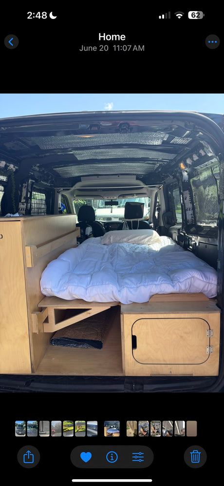 Inside a customized RV rental van: a comfy bed and built-in wooden storage, perfect for road trips.