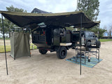 Full overlanding camp setup: A black expedition trailer & Jeep with an extended awning, outdoor kitchen & shower tent. Ideal for rv rental.