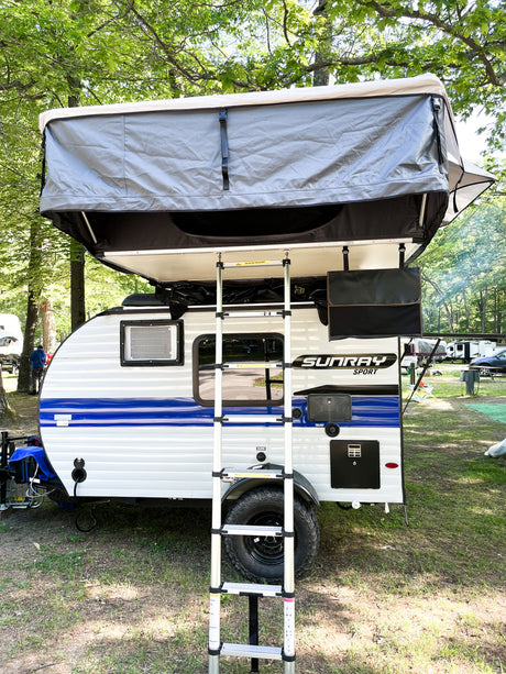 Small white and blue Sunray Sport camper with rooftop tent and ladder, great for an rv rental camping adventure.
