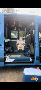 Little one swings inside a blue RV rental van, showcasing family-friendly travel. Perfect for van life adventures!