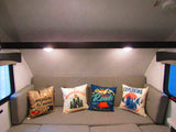 Cozy RV rental interior featuring a bench with four adventure-themed throw pillows, inviting travel and camping comfort.