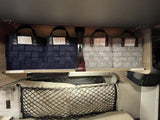 RV rental interior features organized storage: blue & grey woven bins on upper shelf, mesh net below for soft items.