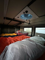 Cozy RV rental interior with multiple beds, a roof vent, and scenic lake views from the windows. Perfect for camping adventures.