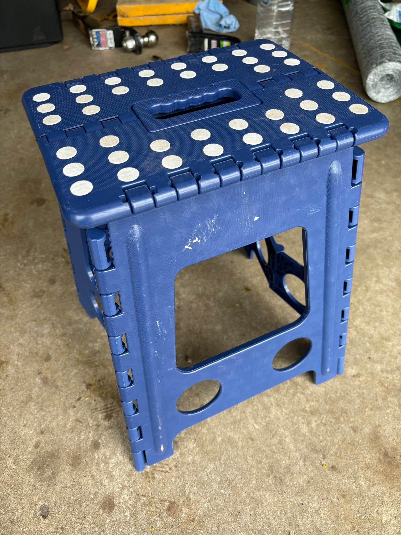 Sturdy blue foldable step stool with white non-slip pads, ideal for an RV rental, set on a concrete floor.