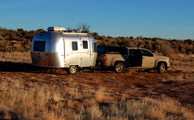 Explore the outdoors with an RV rental: An Airstream trailer hitched to a pickup truck in a scenic, arid landscape.