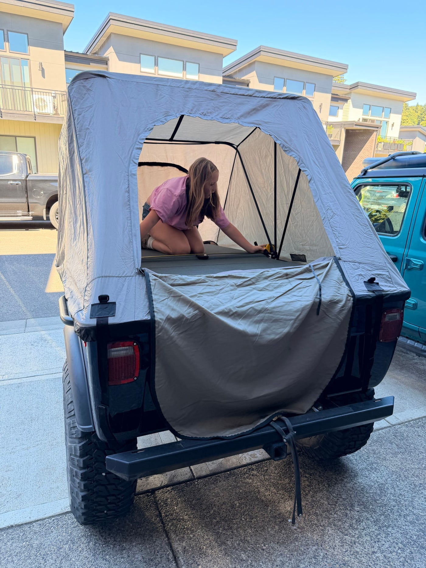 Setting up a vehicle-top tent for an rv rental trip. A person prepares the cozy camping space in the back of an SUV. — photo 4