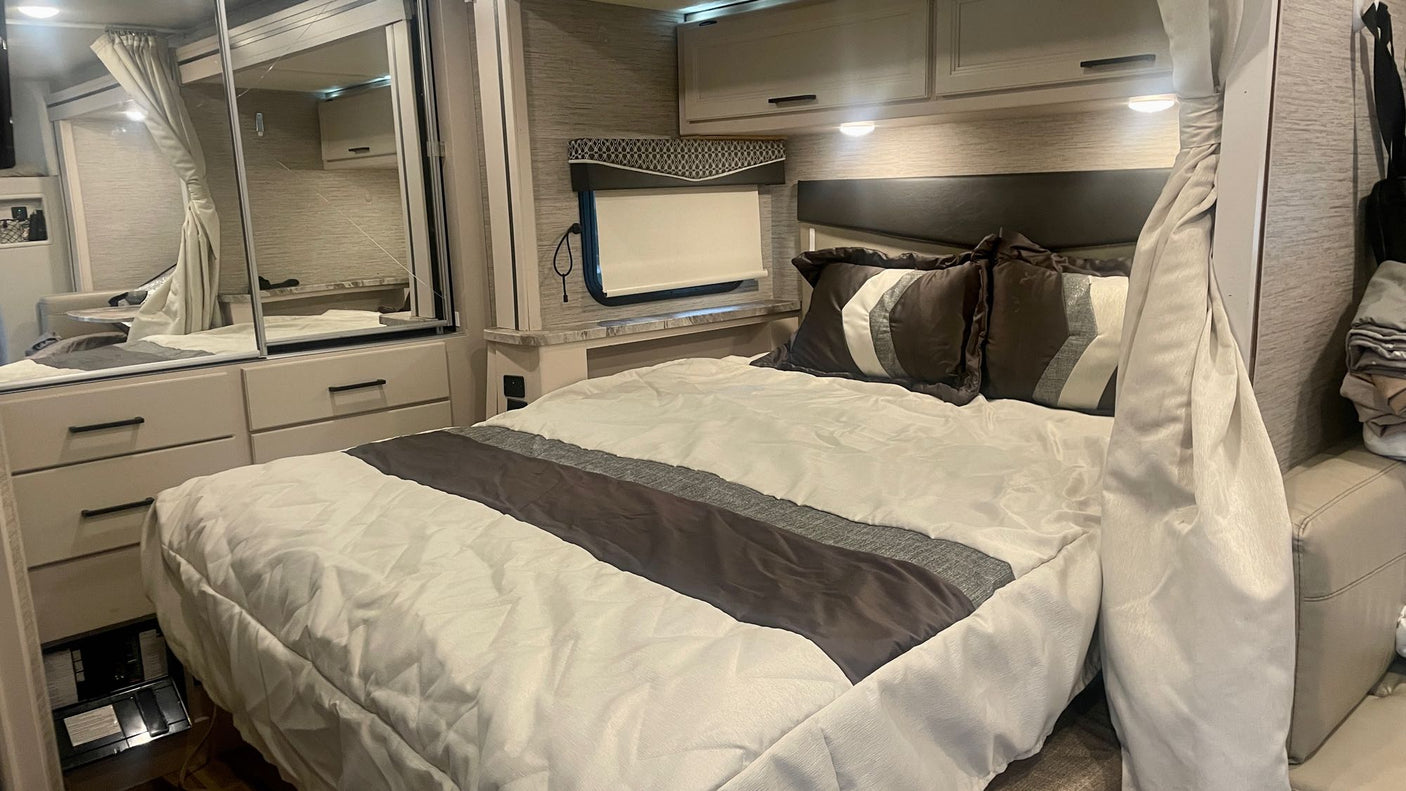 Cozy RV rental bedroom with modern decor, a comfortable bed, mirrored storage, and overhead cabinets.