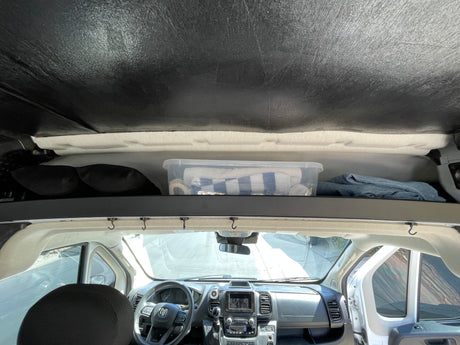 RV rental interior view: overhead storage with bin and blankets, and the vehicle's front dashboard and steering wheel.