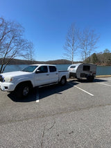 Scenic lake view with a white pickup towing an RV rental. Perfect for outdoor adventures!