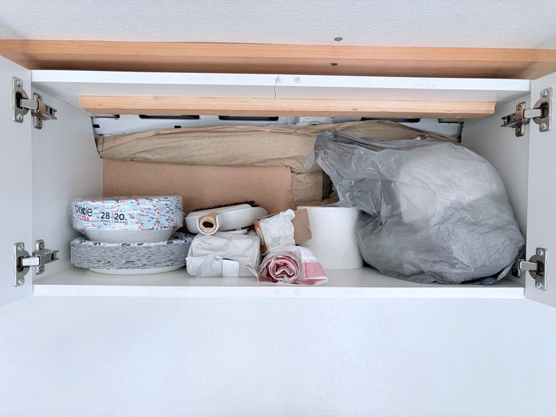RV rental cabinet essentials: paper plates, bowls, toilet paper, and bags packed for your journey. — photo 7