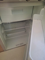 Inside a clean, empty RV rental refrigerator, featuring a top freezer, wire shelves, and door storage.