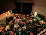 A comfortable floral bed in an rv rental van, illuminated by warm lighting, inviting for travel adventures.