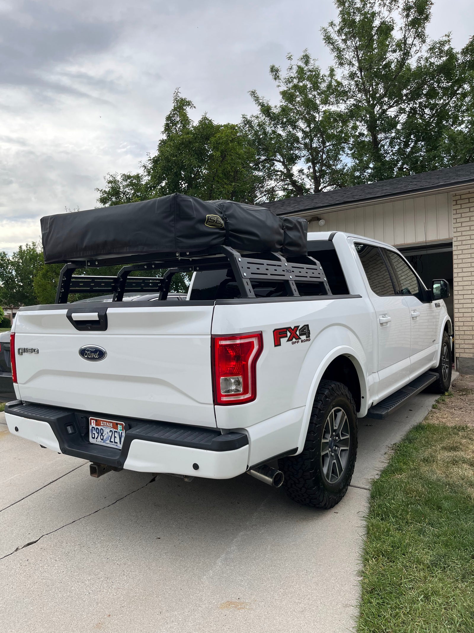 White Ford F-150 truck equipped with an RCI bed rack and black rooftop tent, offering a unique RV rental experience.