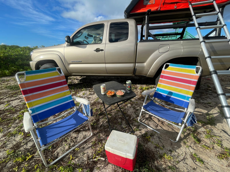 RV rental ready: gold Tacoma truck with rooftop tent, chairs, cooler, & snacks set for outdoor camping. — photo 5