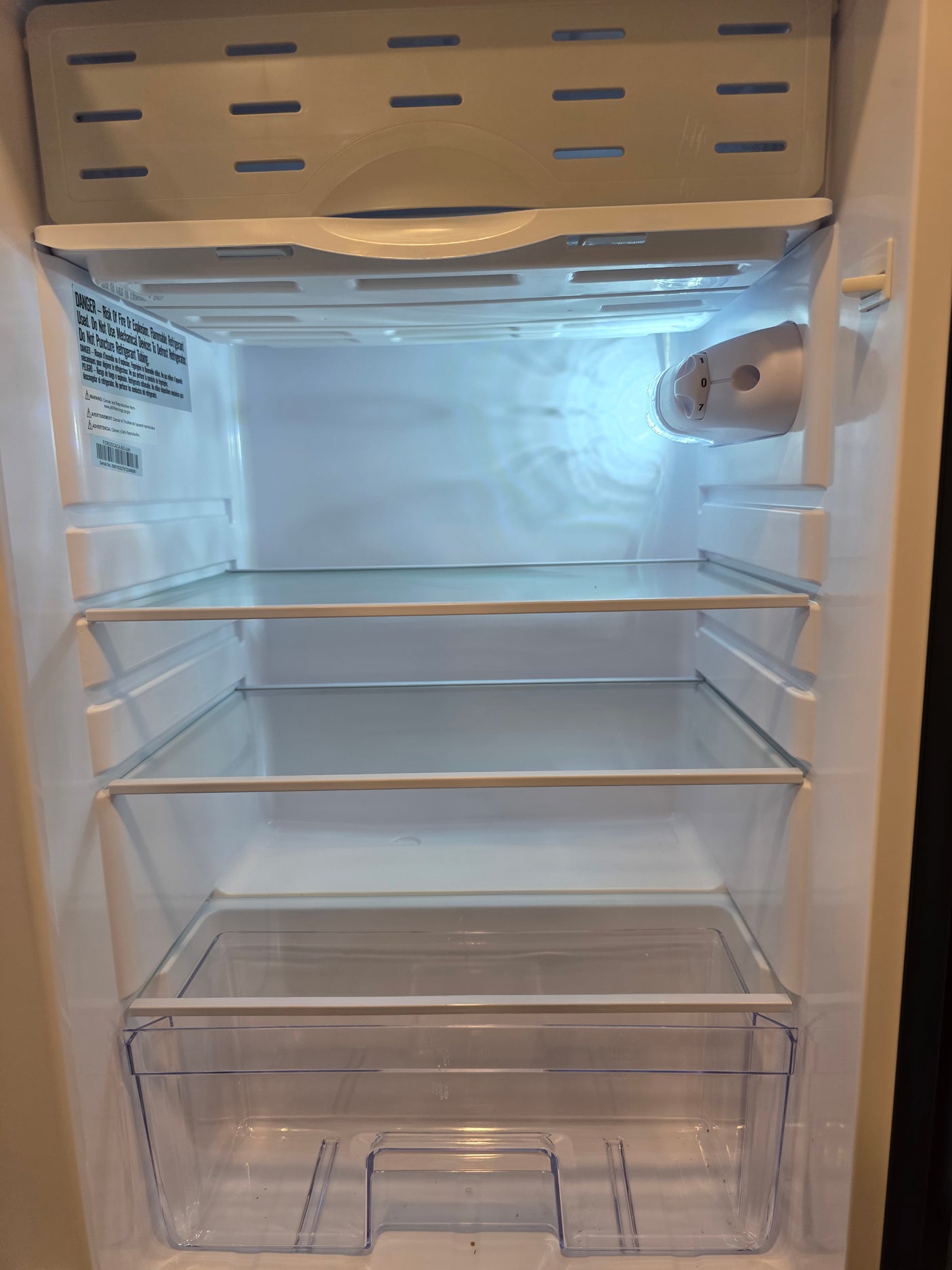 Clean, empty compact refrigerator interior with glass shelves and a crisper drawer, ready for an RV rental.