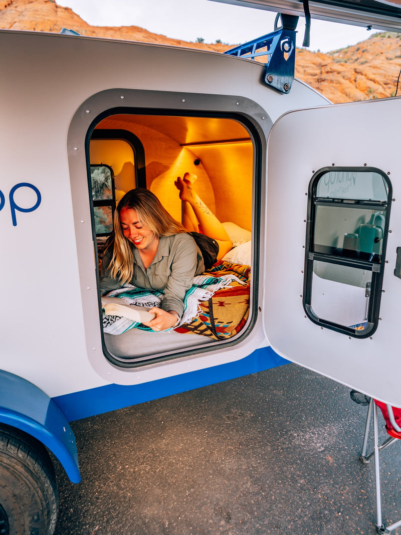 Woman reads in a cozy GoLoop RV rental. Experience comfort in a compact travel trailer, perfect for your next adventure. — photo 4