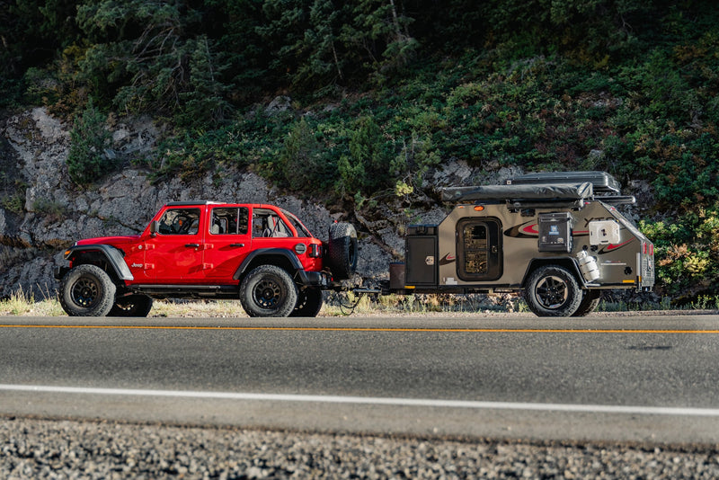 A vibrant red Jeep Wrangler tows a rugged off-road RV trailer on a scenic mountain road. Perfect for your next RV rental adventure. — photo 13
