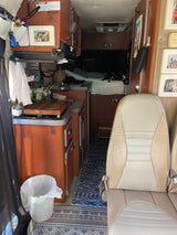Inside an RV rental: a compact kitchenette, rear sleeping area, and front seats, offering a functional mobile living space.