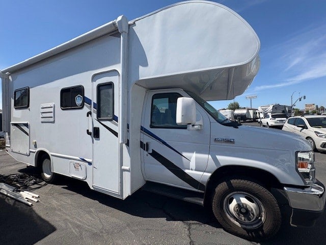 Side view of a clean white Class C RV rental with an awning