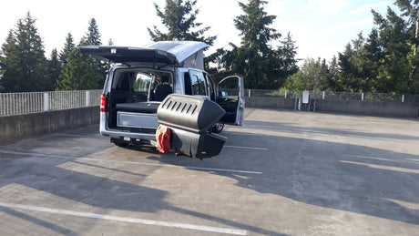 Spacious RV rental ready for adventure: silver camper van with pop-top and rear storage in a parking lot.