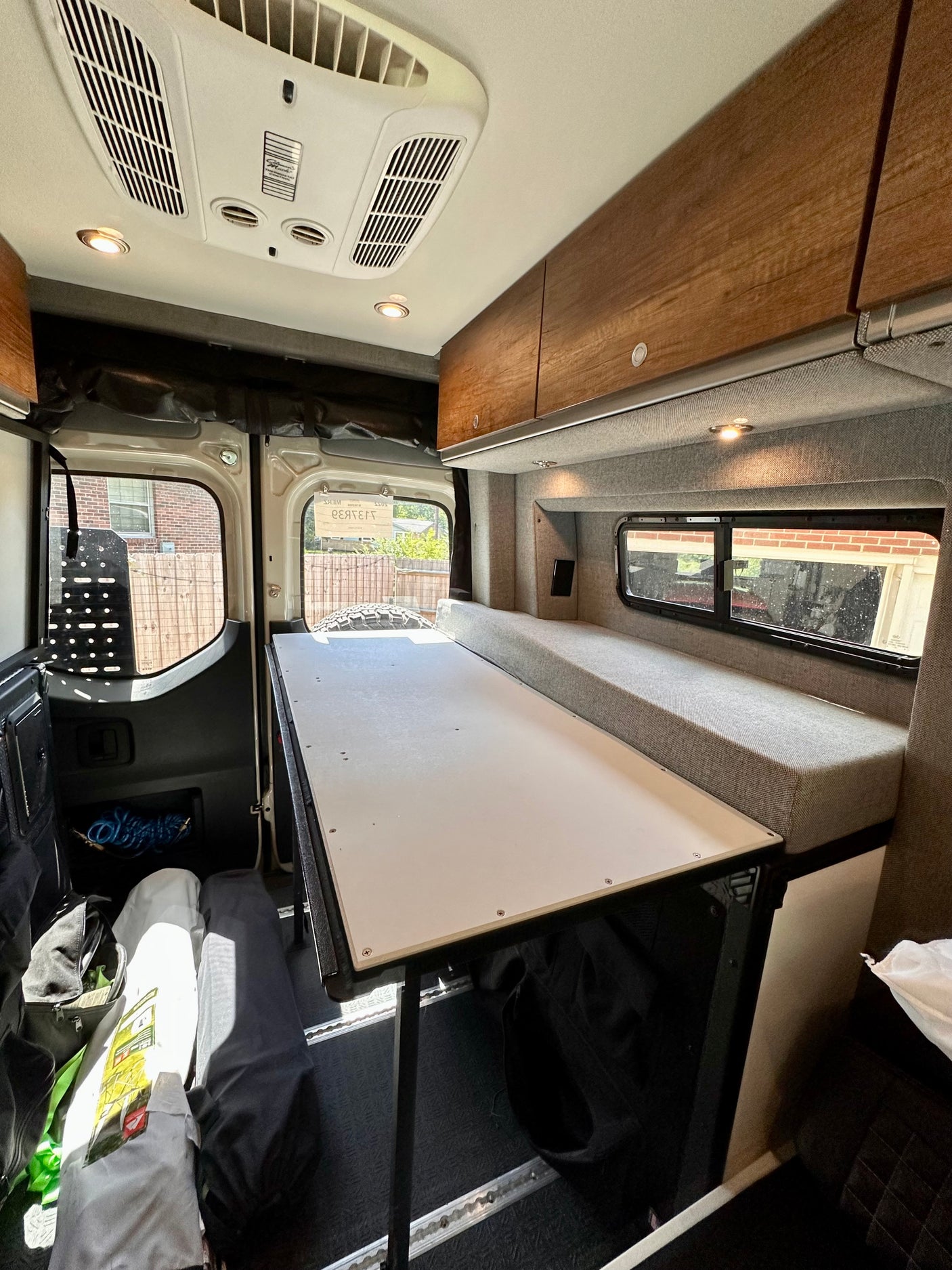 Spacious RV rental interior with a versatile table/bed, comfy bench seating, overhead AC, and storage for road trips.