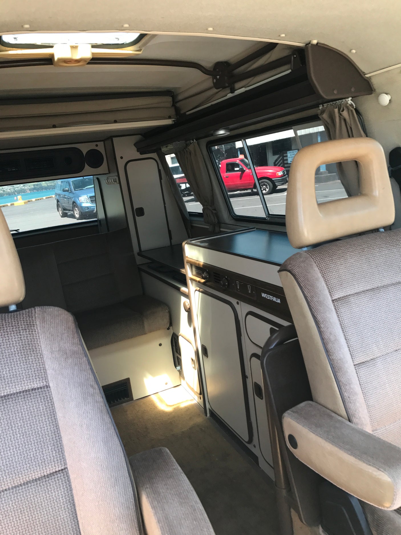 Interior of a Westfalia RV rental, featuring a compact kitchen, comfortable seating, and pop-top roof mechanism.