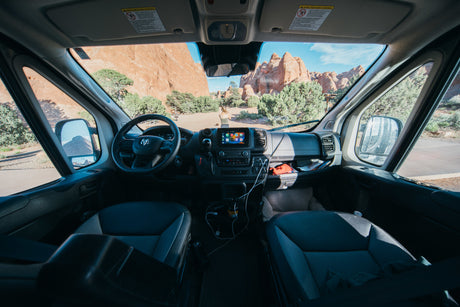 From an RV rental, a scenic road trip view of red rock formations, with a person and dog outside.