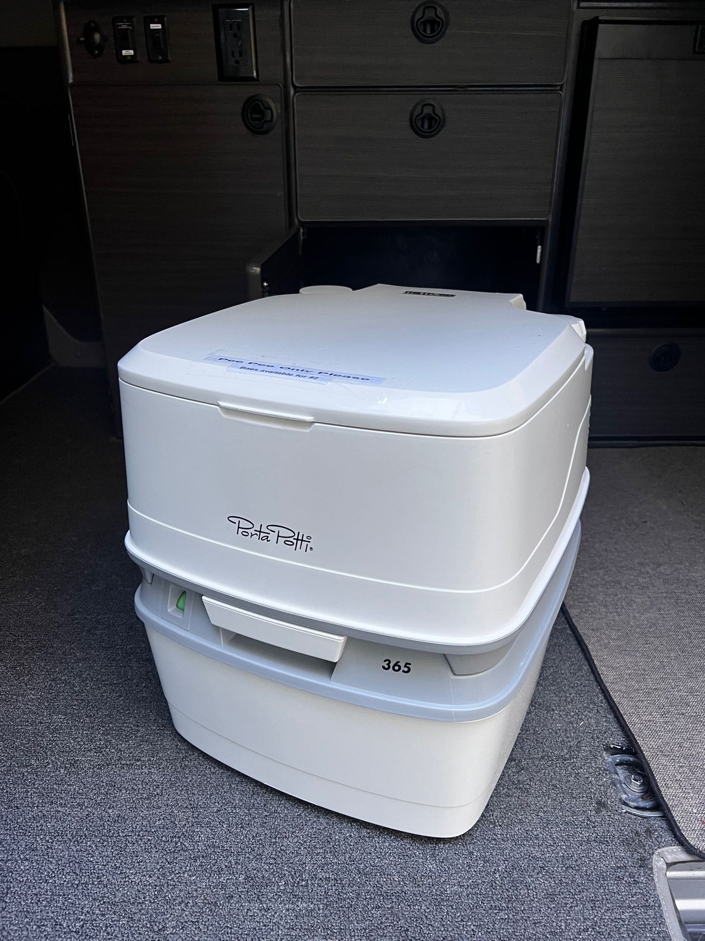 White Porta Potti 365 portable toilet (Pee Pee Only sticker) in an RV rental, ready for travel.