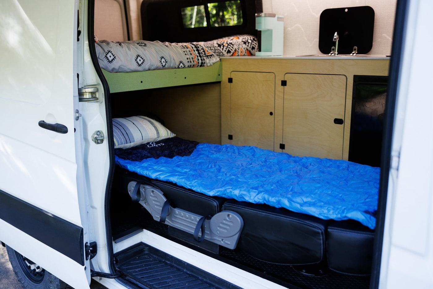 Inside an rv rental camper van, a view through the open door shows bunk beds with sleeping bags and a compact kitchen. — photo 2